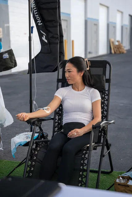 A client receiving IV therapy in a recliner at an outdoor Flow IV event.