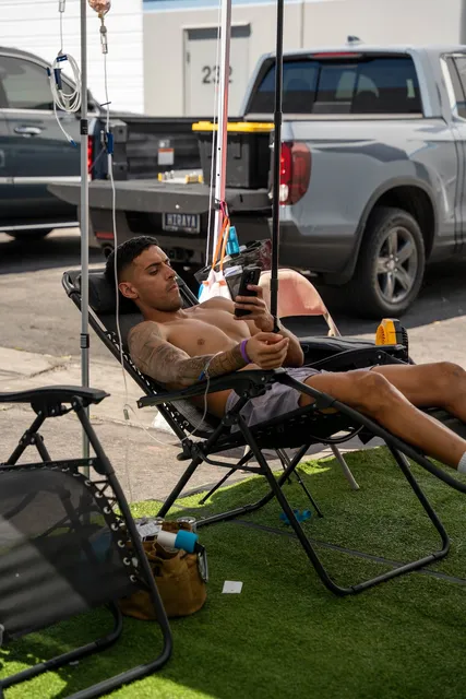 A client reclining with an IV drip at an outdoor Flow IV event.