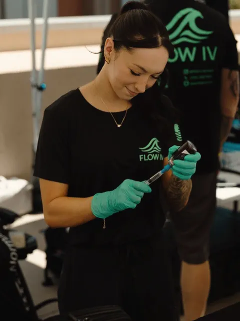 A Flow IV clinician in gloves preparing supplies before a treatment.
