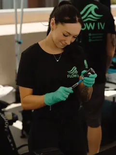 A Flow IV clinician in gloves preparing supplies before a treatment.