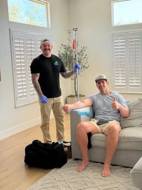 A Flow IV clinician beside a client receiving treatment at home.